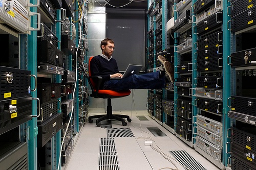 Photograph of a man relaxing in a chair in a datacenter